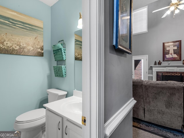 bathroom featuring vanity, a ceiling fan, a fireplace, and toilet