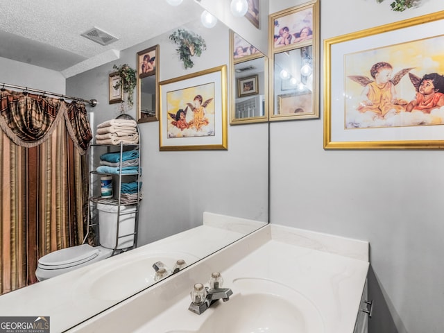 full bathroom featuring vanity, toilet, a textured ceiling, curtained shower, and visible vents