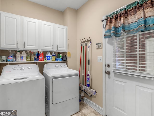 clothes washing area featuring separate washer and dryer, cabinet space, and baseboards