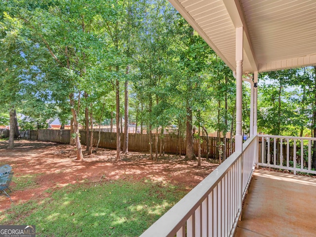 view of yard with covered porch and fence