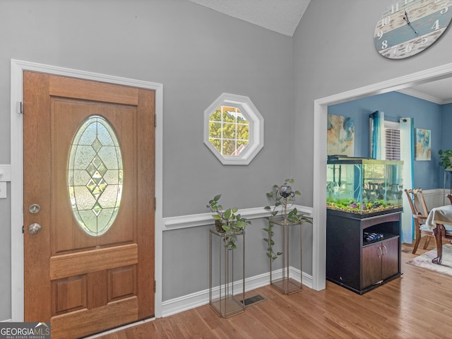 entrance foyer featuring baseboards, visible vents, wood finished floors, and vaulted ceiling
