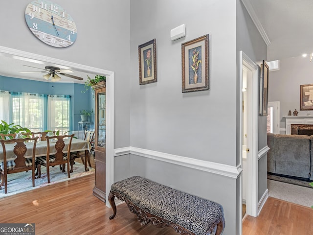 hallway with visible vents, ornamental molding, and wood finished floors