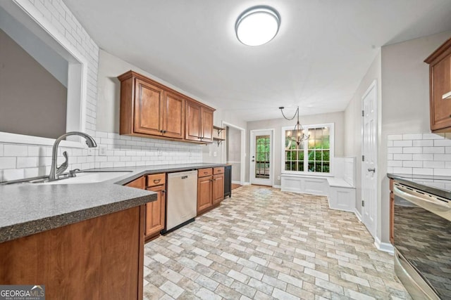kitchen featuring stainless steel dishwasher, dark countertops, dishwashing machine, a sink, and backsplash