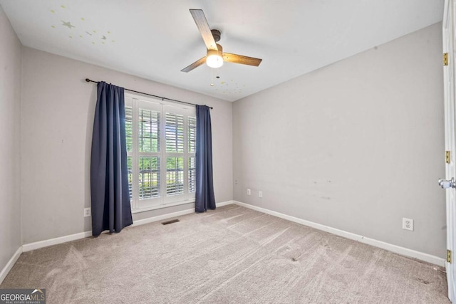 carpeted spare room featuring baseboards, ceiling fan, and visible vents