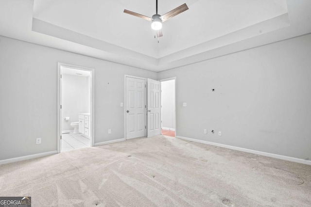 unfurnished bedroom featuring baseboards, a tray ceiling, and carpet flooring