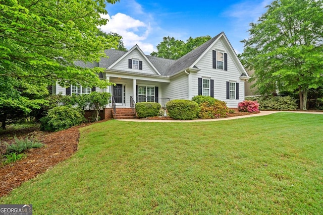 craftsman house featuring covered porch, a shingled roof, and a front lawn