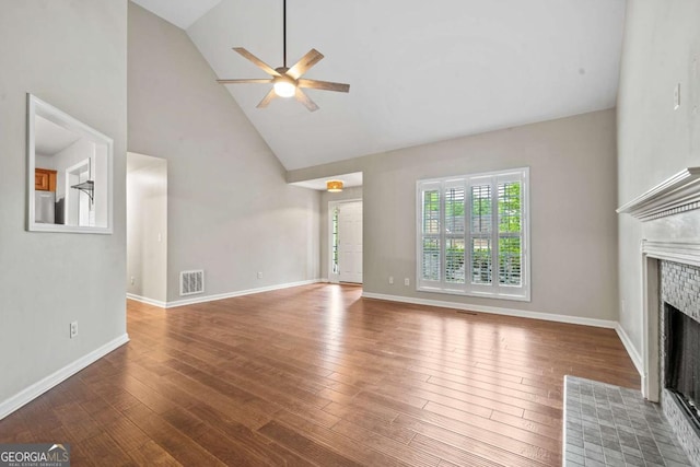 unfurnished living room with high vaulted ceiling, a ceiling fan, a fireplace with flush hearth, wood finished floors, and visible vents