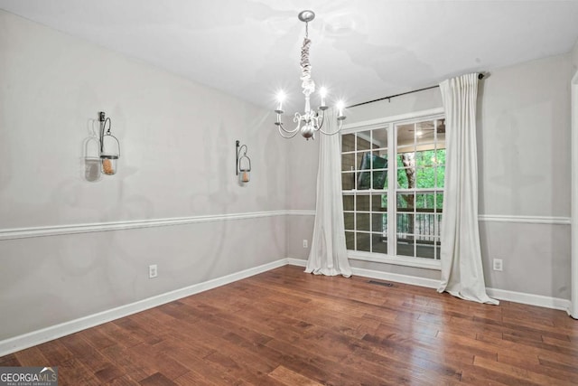 unfurnished dining area with an inviting chandelier, baseboards, wood finished floors, and visible vents