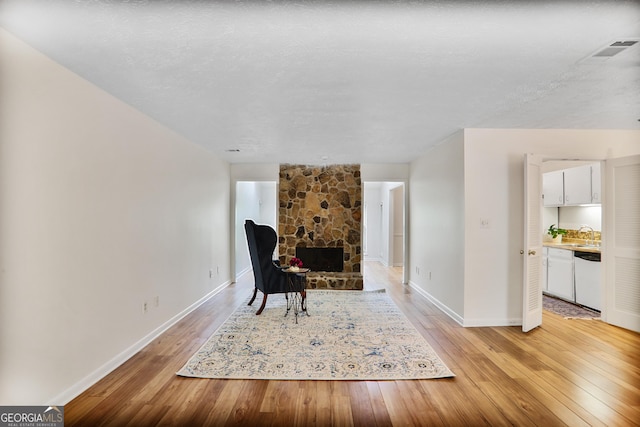 living area with light wood-type flooring, baseboards, visible vents, and a fireplace