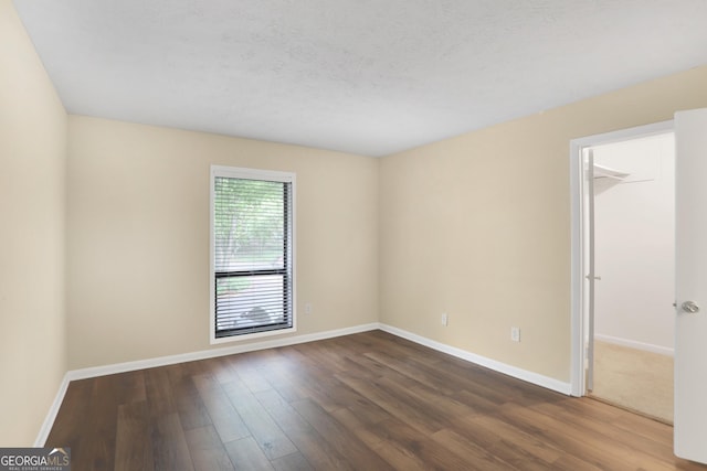 spare room with baseboards and dark wood-style floors