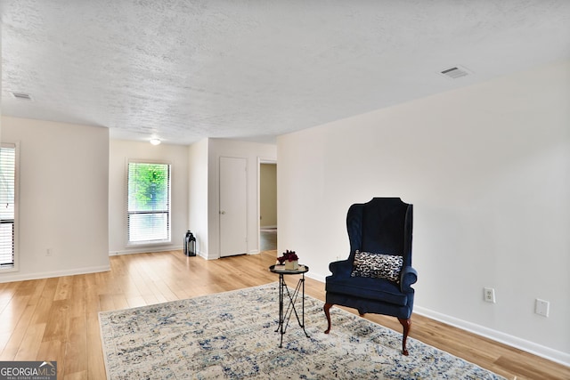 living area with baseboards, visible vents, and light wood-type flooring