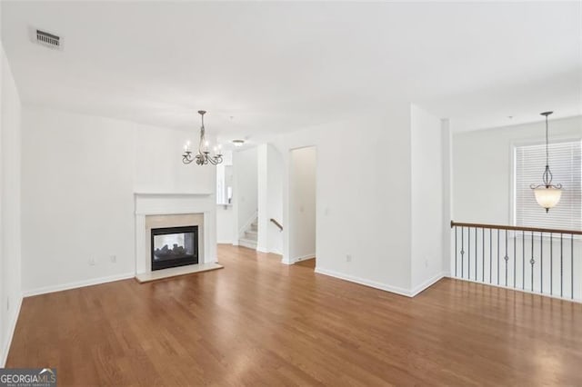 6080 Indian Wood Cir, Mableton, GA 30126 - unfurnished living room featuring visible vents, wood finished floors, baseboards, a multi sided fireplace, and a notable chandelier