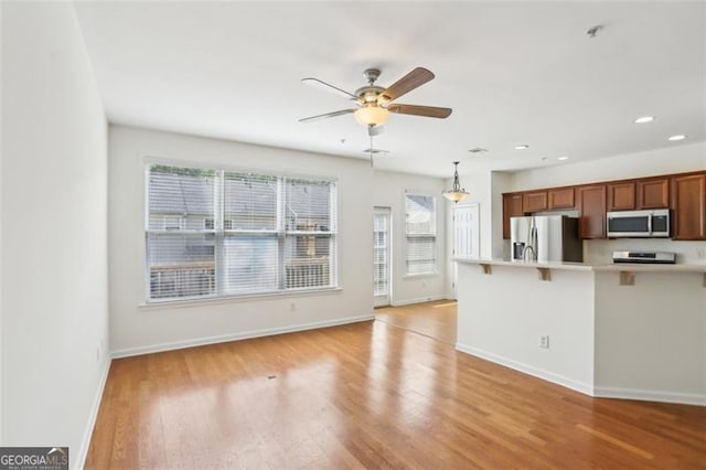 6080 Indian Wood Cir, Mableton, GA 30126 - kitchen with a kitchen breakfast bar, a ceiling fan, appliances with stainless steel finishes, light countertops, and light wood-style floors
