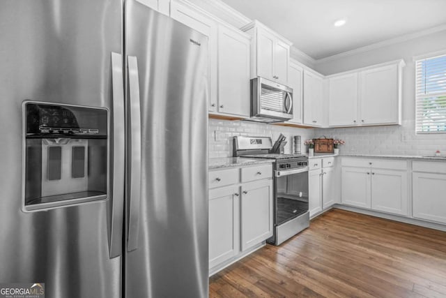 3135 Ellenton Dr, Lithia Springs, GA 30122 - kitchen with stainless steel appliances, crown molding, white cabinetry, light stone countertops, and dark wood finished floors