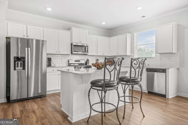 3135 Ellenton Dr, Lithia Springs, GA 30122 - kitchen featuring stainless steel appliances, white cabinetry, light stone counters, ornamental molding, and backsplash