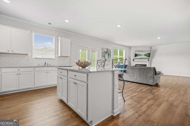 3135 Ellenton Dr, Lithia Springs, GA 30122 - kitchen featuring ornamental molding, open floor plan, a center island, white cabinets, and recessed lighting