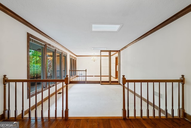 hallway with an inviting chandelier, ornamental molding, wood finished floors, and an upstairs landing