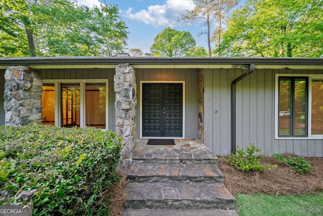 view of exterior entry with covered porch and stone siding