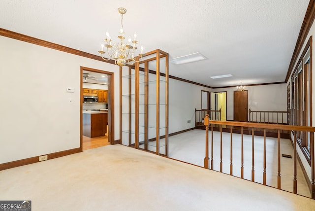 spare room featuring a notable chandelier, ornamental molding, and carpet