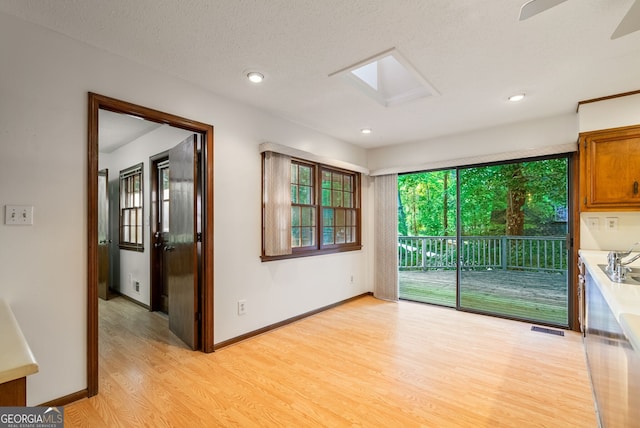 unfurnished room with visible vents, a skylight, baseboards, light wood finished floors, and recessed lighting