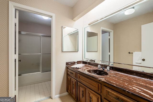 bathroom with shower / bath combination with glass door, wallpapered walls, tile patterned flooring, and vanity