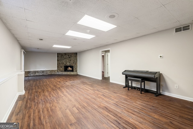 below grade area with a fireplace, a drop ceiling, wood finished floors, and visible vents