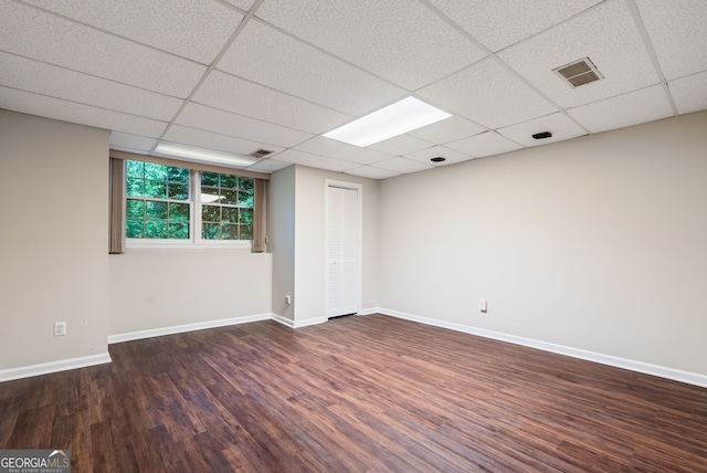 empty room featuring baseboards, a drop ceiling, wood finished floors, and visible vents