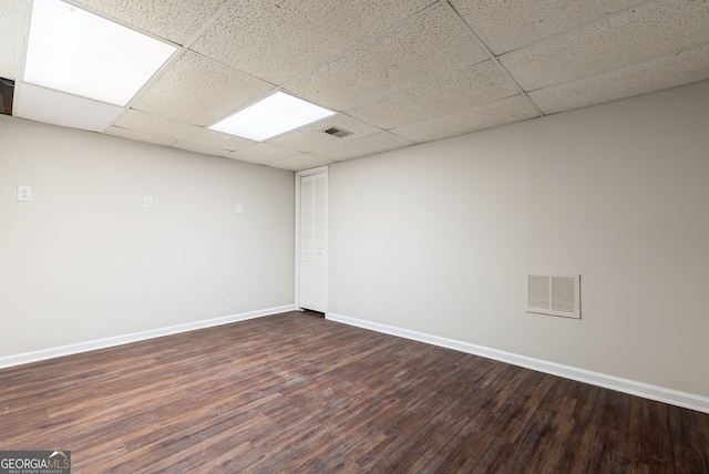 unfurnished room with visible vents, dark wood finished floors, baseboards, and a paneled ceiling