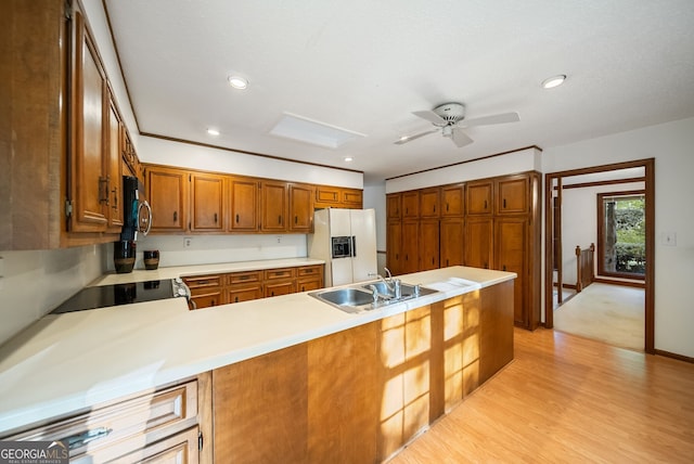 kitchen featuring a sink, white refrigerator with ice dispenser, light countertops, a peninsula, and a ceiling fan