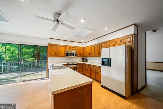 kitchen featuring light countertops, stainless steel appliances, brown cabinetry, and a sink