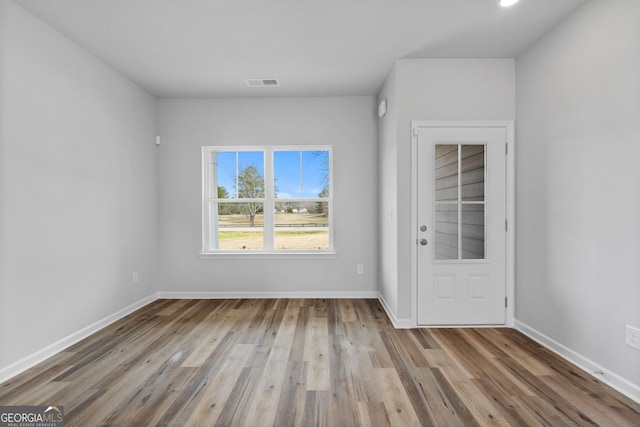 unfurnished room with baseboards, wood finished floors, and visible vents