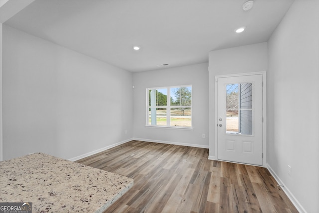 unfurnished dining area featuring recessed lighting, baseboards, visible vents, and wood finished floors