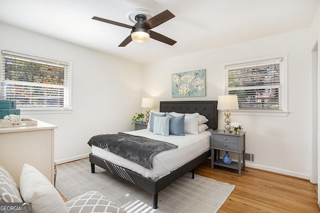 bedroom with baseboards, ceiling fan, light wood-style flooring, and visible vents