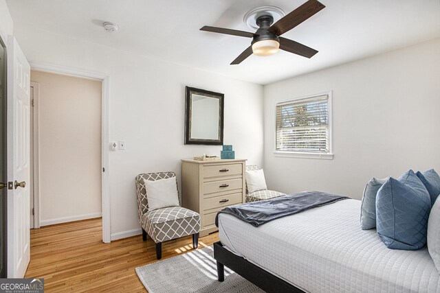 bedroom with light wood-style floors, a ceiling fan, and baseboards