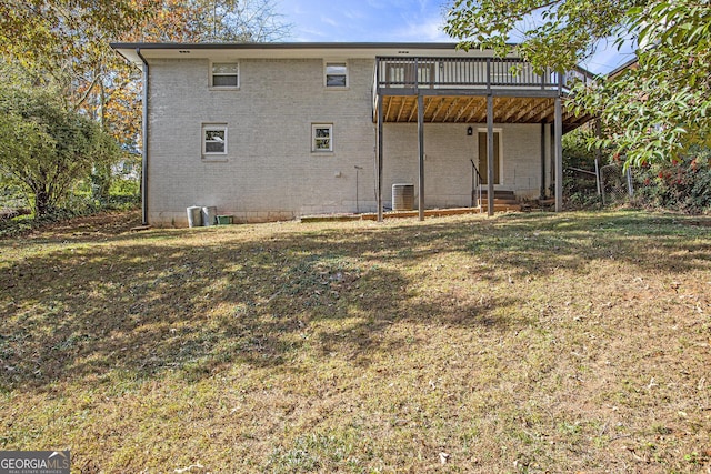 rear view of house featuring a wooden deck, a yard, central AC unit, and brick siding