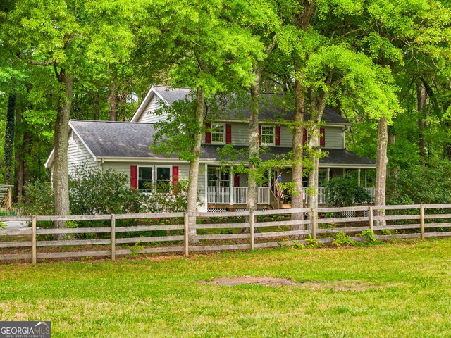 view of front of house featuring fence private yard, roof with shingles, and a front lawn