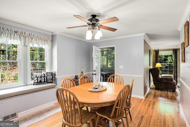 dining area featuring ceiling fan, baseboards, light wood-type flooring, visible vents, and ornamental molding