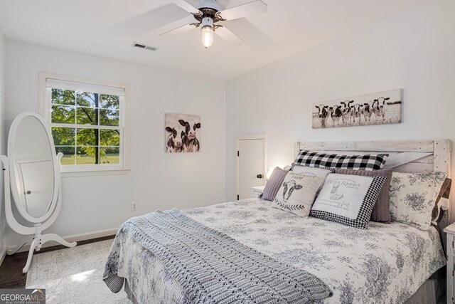 bedroom with baseboards, a ceiling fan, wood finished floors, and visible vents