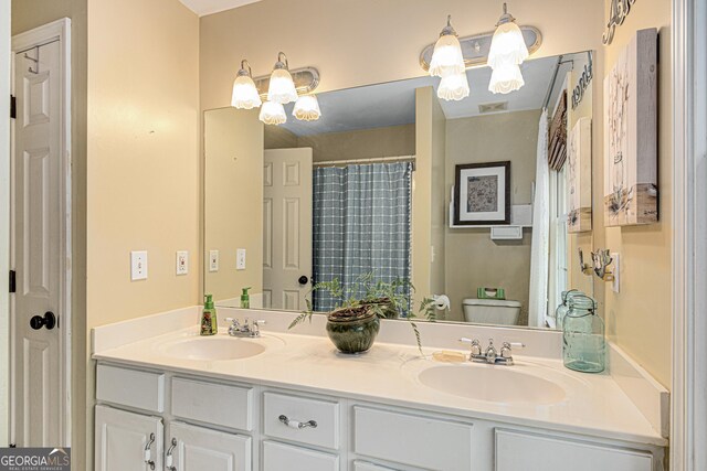 bathroom with a sink, toilet, and double vanity