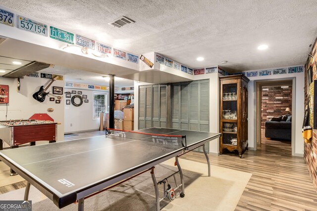 playroom featuring light wood-style floors, recessed lighting, a textured ceiling, and visible vents