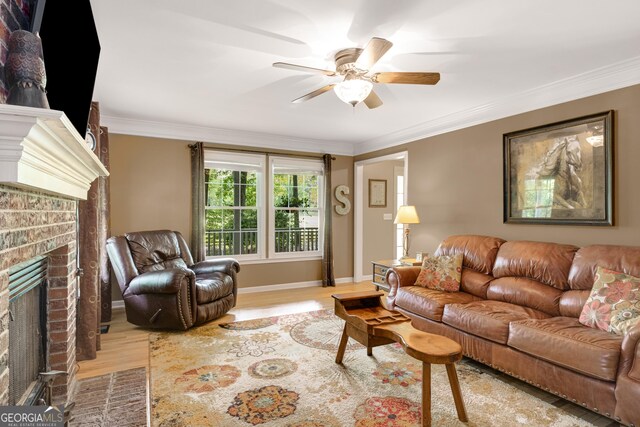 living room with a brick fireplace, a ceiling fan, ornamental molding, and wood finished floors