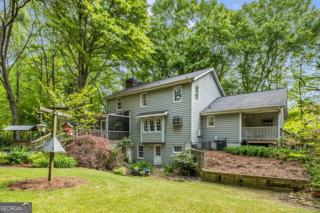 view of front facade with a front lawn, an attached garage, a chimney, a porch, and driveway