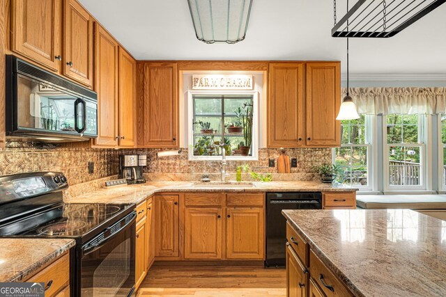 kitchen featuring light stone counters, a sink, black appliances, and tasteful backsplash