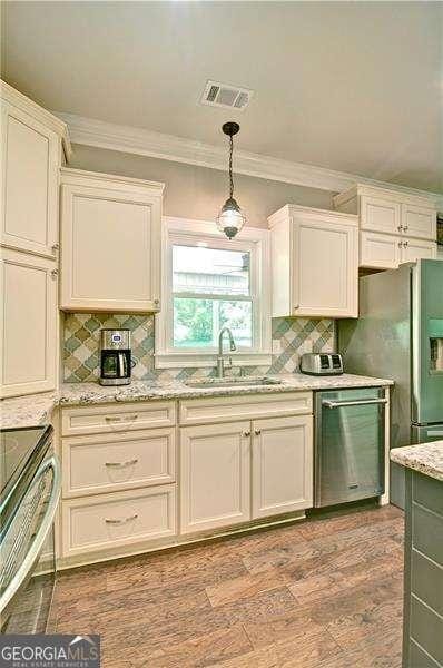5800 Villa Rica Hwy, Dallas, GA 30157 - kitchen featuring stainless steel appliances, crown molding, tasteful backsplash, light stone counters, and hanging light fixtures