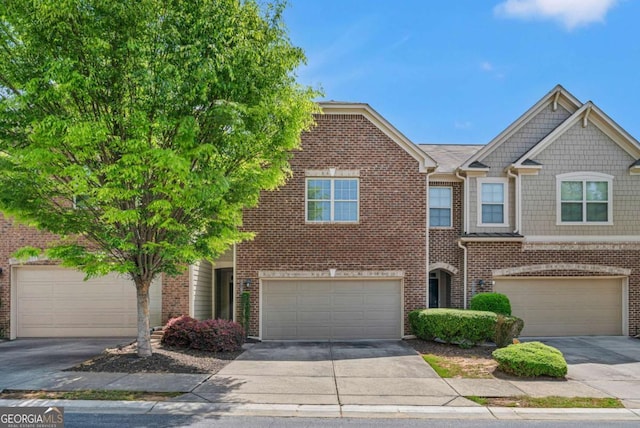 townhome / multi-family property with brick siding, an attached garage, and concrete driveway