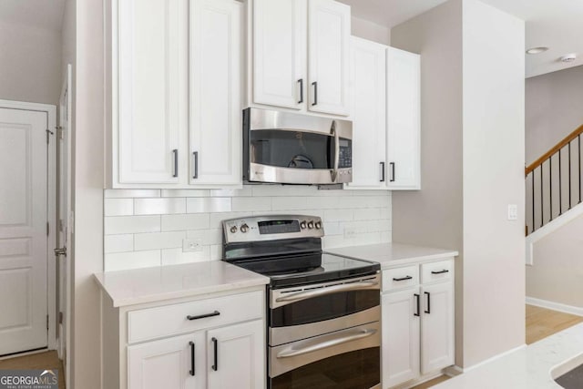 kitchen featuring light countertops, decorative backsplash, stainless steel appliances, and white cabinets