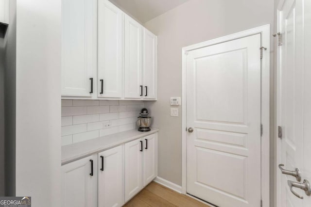 bar featuring light wood-style floors and backsplash