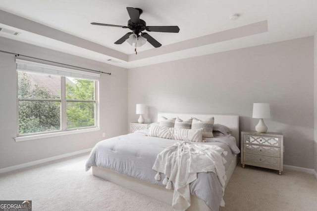 carpeted bedroom with baseboards, ceiling fan, a tray ceiling, and visible vents