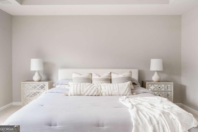 carpeted bedroom with baseboards and a tray ceiling