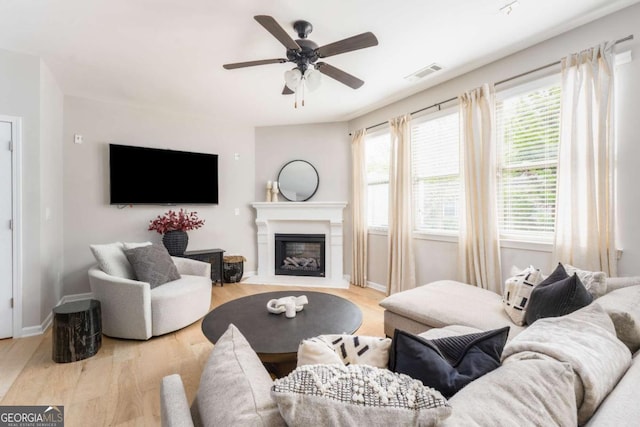 living area featuring a ceiling fan, visible vents, a wealth of natural light, and wood finished floors